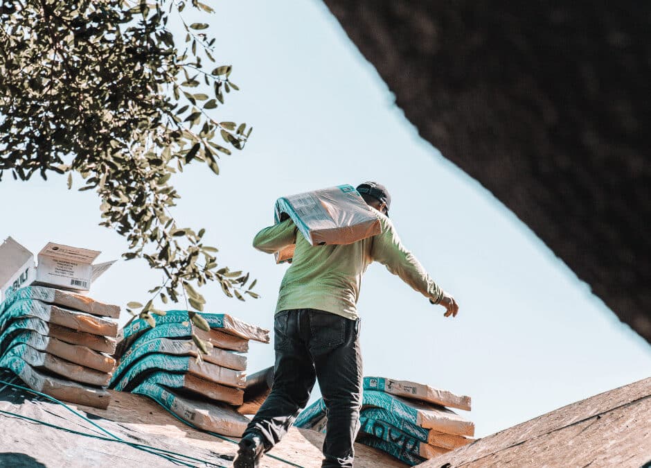 A roofer carrying roof insulation over his shoulder on a roof
